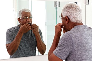 Man with glasses flossing in bathroom