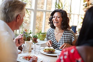 Woman smiling while eating lunch with friends at restaurant